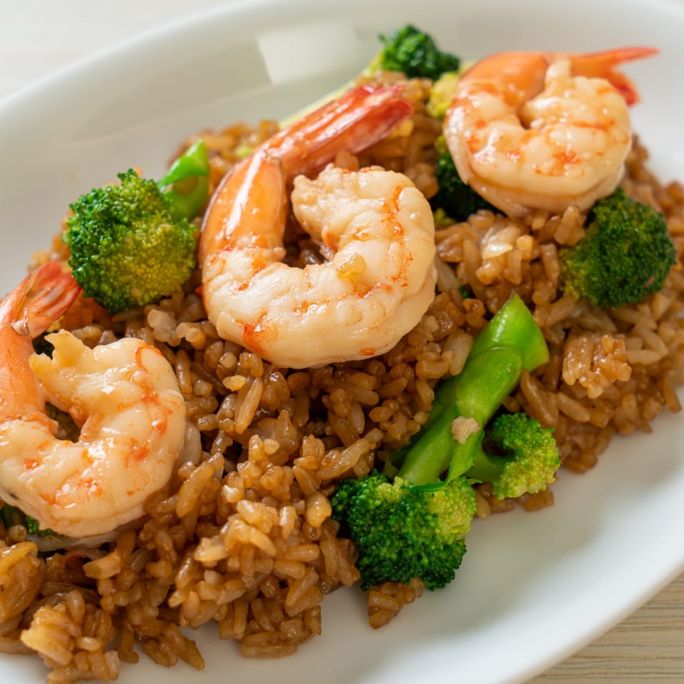 Close-up of shrimp fried rice with broccoli florets on a white plate, a popular Nepalese dish.